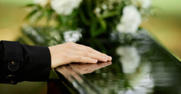 mulher com mão em cima do caixão pós funeral