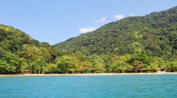 Saiba como funciona o processo de jogar cinzas no mar! Paisagem paradisíaca com águas cristalinas e montanhas ao fundo, cenário ideal para a aspersão de cinzas no mar.