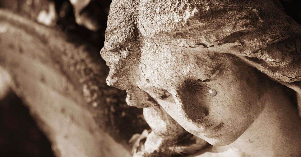 Close de estátua de anjo com lágrima esculpida, expressando como a morte dói e a tristeza.