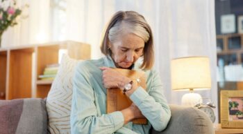 Entenda mais sobre o luto feminino com a Central Crematórios! Mulher idosa abraça porta-retrato com emoção, expressando a dor do luto feminino em casa.