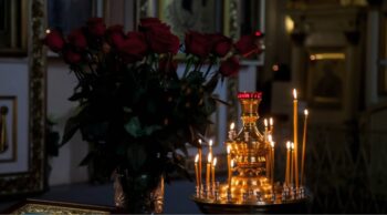 Esclareça suas dúvidas e veja tudo sobre o processo de cremação do início ao fim. Velas finas acesas em candelabro dourado ao lado de rosas no processo de cremação.