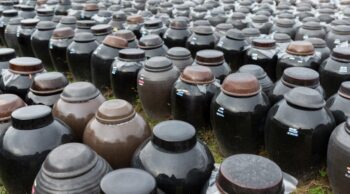 Crenças sobre cremação e rituais de memória. Centenas de urnas e potes cerâmicos organizados em campo aberto, simbolizando diversas crenças sobre cremação.